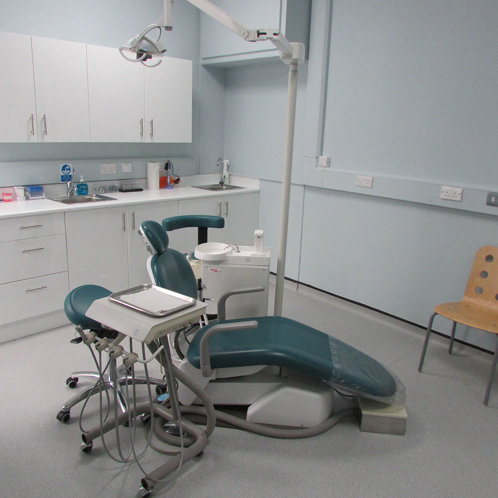Dental office with chair, overhead light, and cabinets.