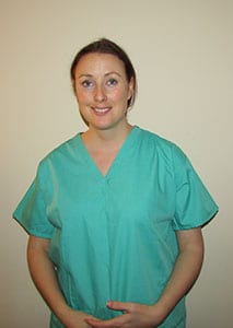 Person in green medical scrubs smiling against a plain background.